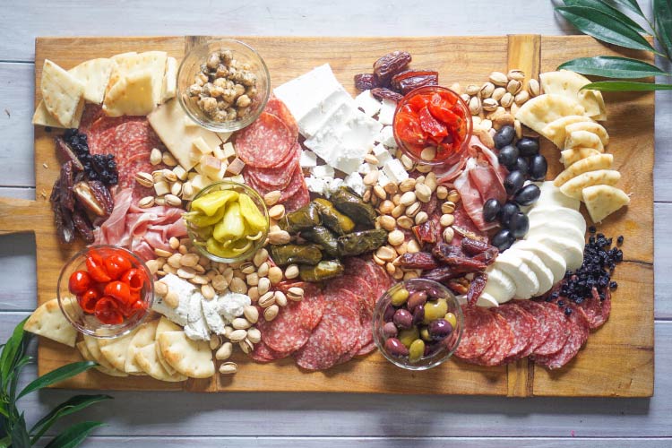 Aerial view of a meat and cheese platter with nuts, olives and grape leaves
