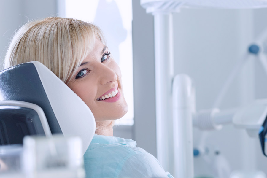 Smiling young blonde woman in the dental chair.
