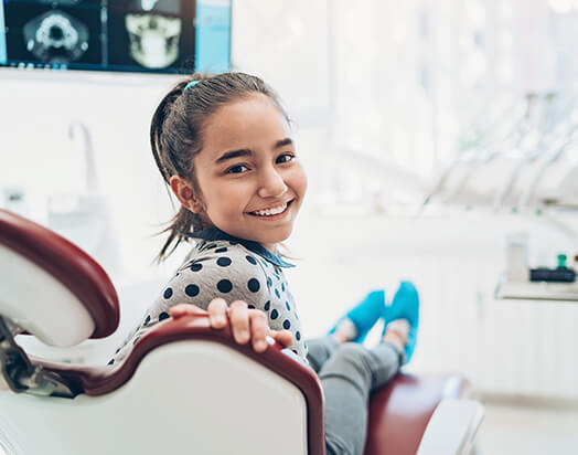 smiling young girl sitting in a dental chair
