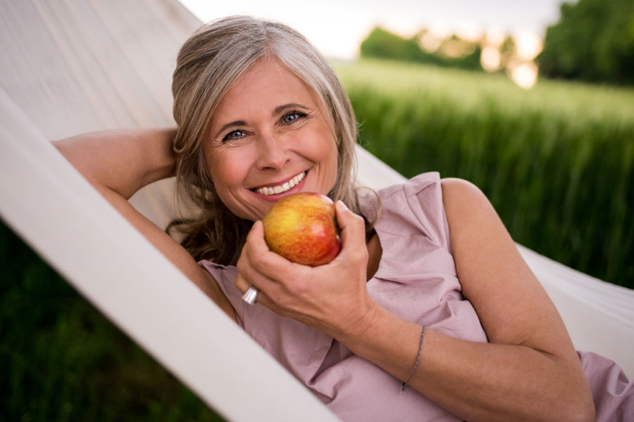 woman relaxes in a lounge chair while eating an apple