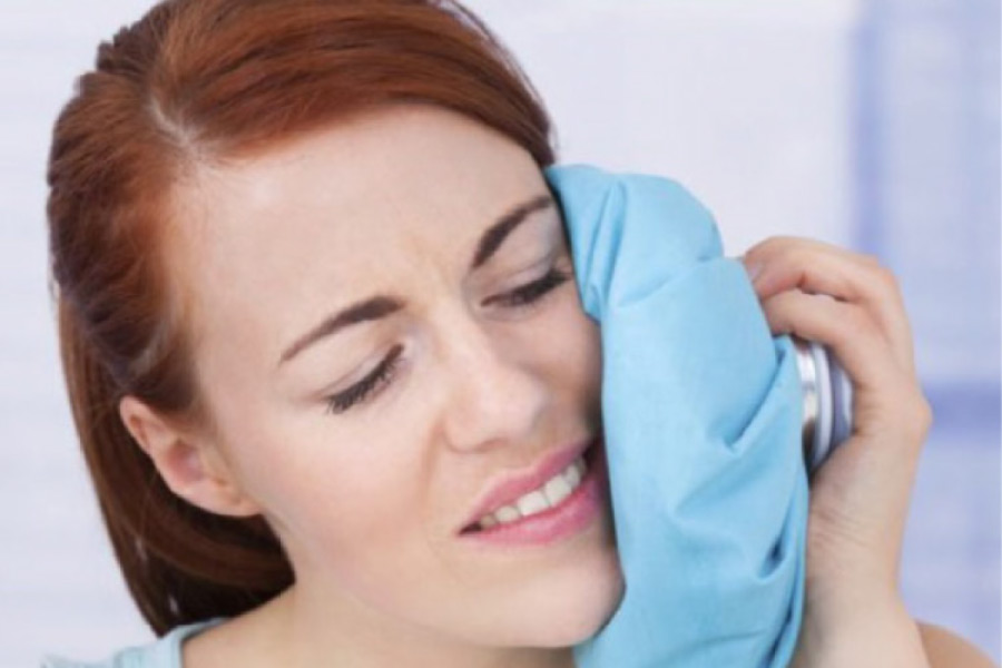 woman holds an icepack to her jaw to help with a toothache